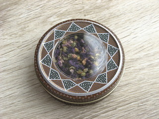 Dried flowers of malva sylvestris nto a handcraft box on wooden table. Close up. Medicine herb.