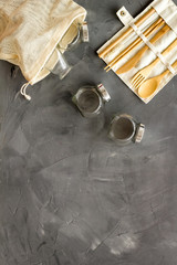 Set of eco friendly bamboo tableware, cotton bag, paper mug and glass jars. Sustainable lifestyle, plastic free concept on brown table - top view