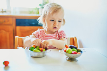 Little girl playing with toy fruits and vegetables