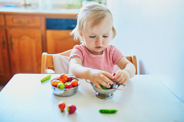 Little girl playing with toy fruits and vegetables