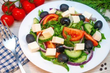 Greek salad with tomatoes, cucumbers and feta cheese with olives on the table