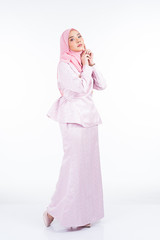 Full length portrait of a beautiful female model wearing traditional dress and hijab, a lifestyle apparel for Muslim women isolated on white background. Idul Fitri and hijab fashion concept.