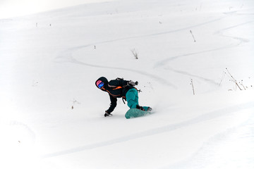 Snowboarder energetically skiing in high mountains at beautiful snowy day.