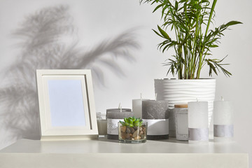 Countertop with green plant and succulent in pots, different sized candles, photo frame, jar with wooden lid, copy space. Isolated on white. Close up