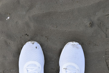Fototapeta premium White Sneakers shoes walking on sand top view, running shoes walking on Sand