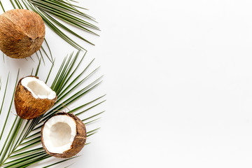 Fototapeta na wymiar Coconuts frame. Nuts pieces and exotic leaves on white background top-down copy space