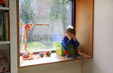Fototapeta na wymiar Ein vierjähriger Junge sitzt gelangweilt in seinem Zimmer am 18.03.2020.