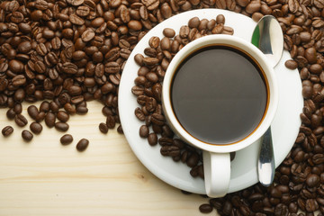 top view of coffee cup with coffee beans and steel spoon on wooden table. flat lay. free copy space for your text