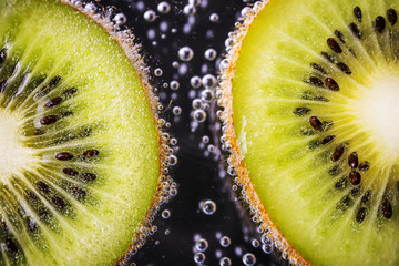 A slices of ripe juicy kiwi in mineral water. Detailed macro photo. The concept of summer...