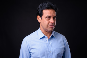 Obraz premium Mature handsome Indian businessman against black background
