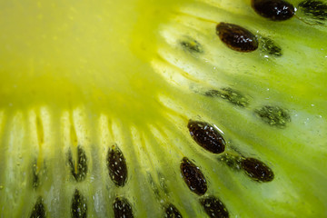 A slice of ripe juicy kiwi closeup. Detailed bright macro photo. The concept of fruit harvest, vegetarianism, useful healthy food, vitamins. Abstract food image.