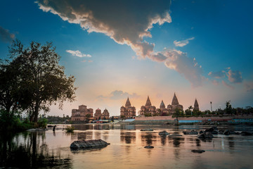 Naklejka premium Sunset view of chhatri or canopies at Orchha from across the betwa river in Orchha Madhya Pradesh India.