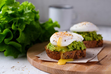  Fresh vegetarian bruscetta with avocado, lime and poached eggs at wooden board on white background