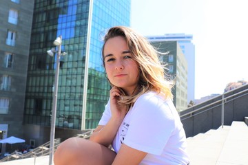 Fototapeta premium mujer joven con camiseta blanca sentada en escaleras en una ciudad