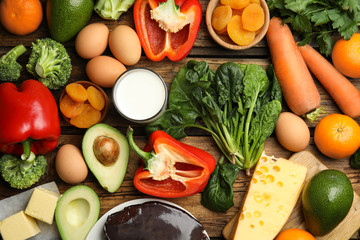 Fresh products rich in vitamin A on wooden table, flat lay
