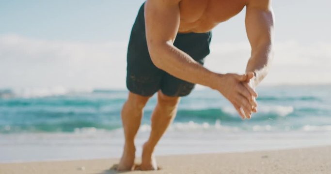 Strong muscular man doing clap push ups on the beach as a part of his morning workout routine, focused fit man strengthening his body and mind