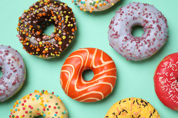 Delicious glazed donuts on turquoise background, flat lay