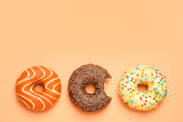Delicious glazed donuts on orange background, flat lay. Space for text
