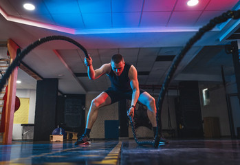 Young man workout with battle ropes.