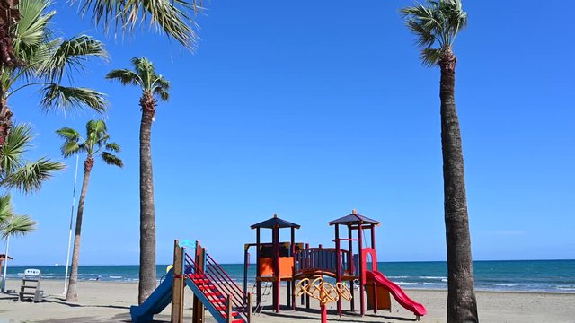 Lifeguard's cabin and a palm located on Mackenzie Beach. Waves of the Mediterranean sea on the background. Sunlight shot. Larnaca, Cyprus