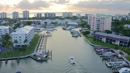 Boat entering Bonita Springs Florida docks aerial fly over Sunset