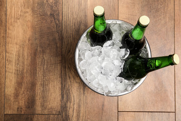 Beer in metal bucket with ice on wooden background, top view. Space for text © New Africa
