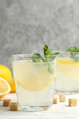 Lemonade, lemons and sugar cubes on wooden background, space for text