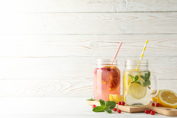 Glass jars with lemonade on wooden background. Fresh drink