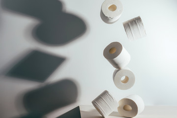 Falling rolls of toilet paper on white background with dark shadow. Concept of crisis, quarantine,...