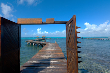 Wooden pier extending over the Caribbean sea. Open doors overlooking the Caribbean ocean