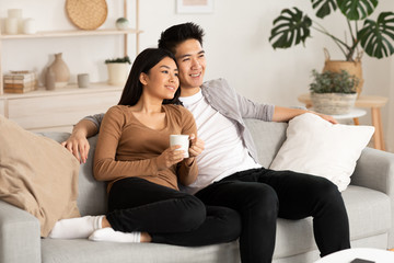 Obraz premium Filipino couple resting at home and watching tv