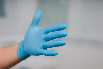 hand in medical gloves  in front of a clinic room