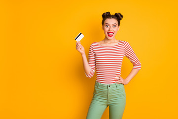 Photo of pretty excited funny lady open mouth holding credit card wireless online money wear striped red white shirt green pants isolated bright yellow color background
