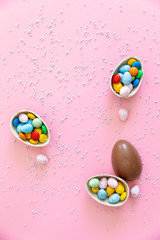 Broken Easter chocolate eggs and colorful decorations on a light background. Banner. Easter concept, easter treats. Flat lay, top view