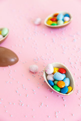 Fototapeta na wymiar Broken Easter chocolate eggs and colorful decorations on a light background. Banner. Easter concept, easter treats. Flat lay, top view