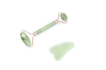 Green face roller and gua sha massager made from natural jade nephritis stone isolated on white...