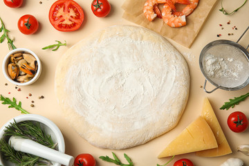 Flat lay composition with dough and fresh ingredients for seafood pizza on beige background