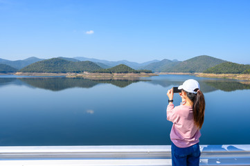 Back view of young tourist woman taking a picturesque of the nature in Mae Kuang Dam, Chiang Mai province of Thailand. Mae Kuang dam is a medium-sized reservoir used to facilitate water into the city.