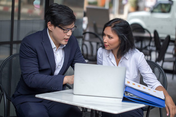 Male employee friend and a private business owner are discussing investment and life insurance consultations. See information from laptop at coffee shop. 