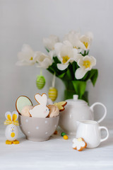 Easter table setting with bunnies, gingerbread, eggs and flowers. Happy Easter Greeting Card Template. Easter cake and colorful eggs on festive table. The concept of family celebration.