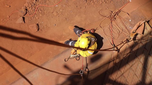Safe work practices topeview 4K high quality footage of rope access welder worker wearing full safety harness equipment disconnecting secondary safety backup device in the safe manner Australia   