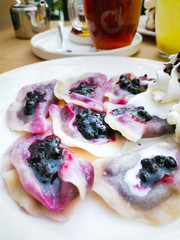 delicious sweet polish dumplings stuffed with blueberries jam and blueberries for toppings served with vanilla ice cream and Whipped cream in white plate