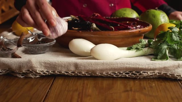 Woman placing a bulb of garlic on a tray with assortment of herbs and spices