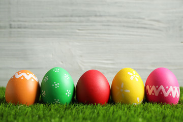 Colorful Easter eggs on green grass against white background. Space for text