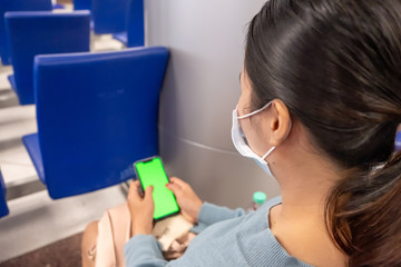 Thai lady texting on the phone at the airport. Asian girl use a protection mask for coronavirus or covid 19 in airport. 