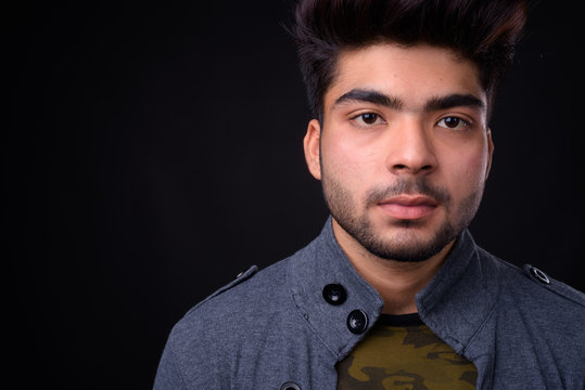 Young handsome Indian man against black background