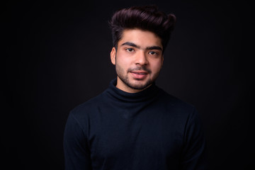 Young handsome Indian man against black background