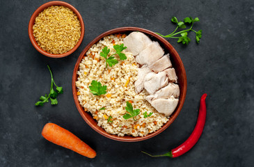 Bulgur with vegetables and chicken fillet on a stone background.