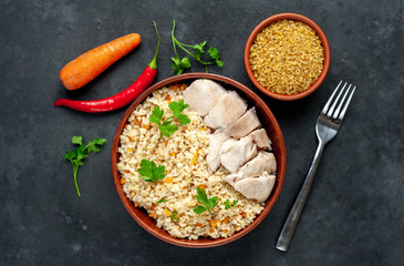 Bulgur with vegetables and chicken fillet on a stone background.