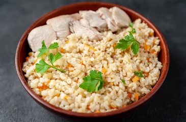 Bulgur with vegetables and chicken fillet on a stone background.